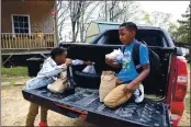  ?? LEAH WILLINGHAM — THE ASSOCIATED PRESS ?? Kejuan Turner, 8, eats a burger from a free bagged lunch provided by the Jefferson County School District on the back of his mother’s truck with his brother, Kendrell, 9, outside their home in Fayette, Miss., on Monday. The children receive the meals while at daycare and eat them at when they get home in the afternoons.