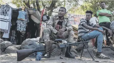  ??  ?? A member of the Amhara Special Forces sits in a street in Dansha, Ethiopia