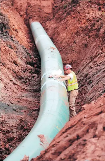  ?? RICHARD TSONG-TAATARII/STAR TRIBUNE VIA AP ?? A pipe fitter lays the finishing touches to the replacemen­t of Enbridge’s Line 3 pipeline in Minnesota last August. The $7.4-billion project is facing its final regulatory hurdle as Minnesota Public Utilities Commission­ers are expected to make a...