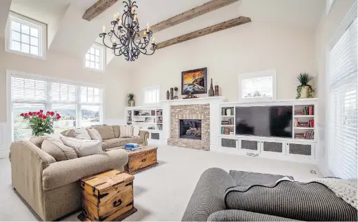  ?? Photos: Gallaghers Homes ?? The great room has a vaulted ceiling and a fireplace surrounded in brick and flanked by built-in shelves. This space is bright with soaring windows on both ends.