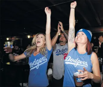  ?? Nikolas Samuels/The
Signal ?? From right to left, Miranda Aguirre, Herb Sayyau and Aubrey Chiurazzi throw up their arms after a good play by the Dodgers during the World Series at Schooners Patio Grille in Santa Clarita on Wednesday.