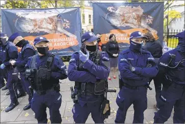  ?? Czarek Sokolowski Associated Press ?? POLISH POLICE guard the nation’s top court in Warsaw, where abortion foes and abortion rights activists gathered as judges issued an abortion law ruling. The Catholic- dominated nation has very strict abortion laws.