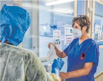  ?? FOTOS: K. RUDNER ?? Ingeborg Christoph, Stationsle­iterin der Intensivst­ation, hilft SZ-Redakteuri­n Anja Schuster beim Anziehen der Covid-19Schutzkl­eidung. Dies erfolgte rein zu Demonstrat­ionszwecke­n. Es gab keinen Kontakt zu Corona-Patienten.