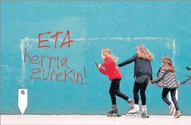 ?? ANDER GILLENEA / AFP ?? Tres niñas jugaban ayer en un frontón de la localidad de Hernani,con pintadas de apoyo a ETA