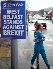  ??  ?? A woman walks past a Sinn Fein poster opposing Brexit in Northern Ireland on Tuesday.