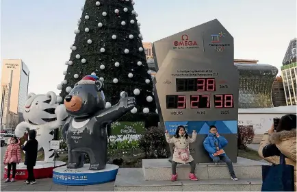  ?? PHOTO: AP ?? Children pose for photos in front of a display in Seoul showing the number of days left until the opening of the Pyeongchan­g Winter Olympic Games.