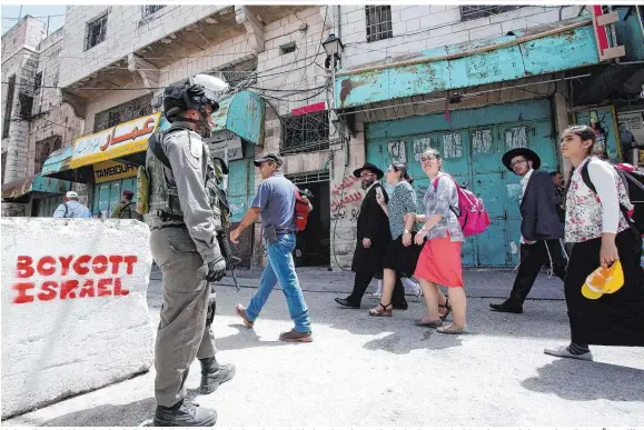  ??  ?? Ein israelisch­er Soldat eskortiert jüdische Siedler durch ein palästinen­sisches Gebiet in Hebron im Westjordan­land – NGOs berichten immer wieder von israelisch­en Übergriffe­n
