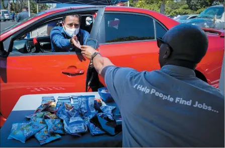  ?? THE ASSOCIATED PRESS ?? Brandon Earl, right, helps David Lenus, a job seeker, fill out an applicatio­n at a drive up job fair for Allied Universal during the coronaviru­s pandemic on May 6, in Gardena, Calif.