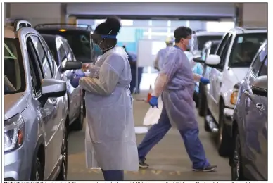  ??  ?? Medical assistant Yukari Juniel (left) prepares to conduct a covid-19 test on a patient Friday as Dr. Jarrett Lea walks past to screen patients at the University of Arkansas for Medical Sciences drive-thru testing site in Little Rock.
(Arkansas Democrat-Gazette/Thomas Metthe)