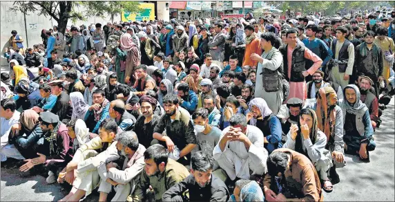  ?? AFP ?? A LONG WAIT: People sit along a road outside a bank waiting to withdraw money at Shar-e-Naw neighbourh­ood in Kabul, Afghanista­n on Saturday.