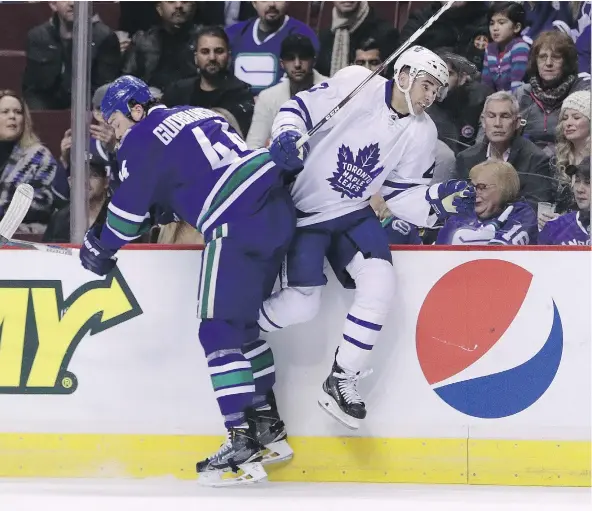  ?? — THE CANADIAN PRESS ?? Vancouver’s Erik Gudbranson throws a hip into Toronto’s Nazem Kadri along the boards during the first period at the Rogers Centre Saturday night. At just 24, Gudbranson seems to be a grizzled veteran when compared to Toronto’s young stars.