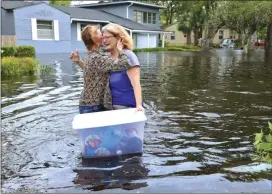 ?? The Associated Press ?? Charlotte Glaze gives Donna Lamb a teary hug as she floats out some belongings Monday in Jacksonvil­le, Fla., after Hurricane Irma passed through the area. “This neighbourh­ood has not flooded in at least 51 years,” Lamb said.