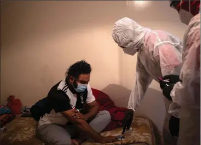  ?? (AP/Bram Janssen) ?? Paramedics from the Saaberie Chishty ambulance service attend to a covid-19 patient at his home in Lenasia, South Africa.