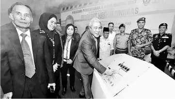  ??  ?? Awang Tengah signing the DBPRO as a symbolic launch of the product at Unimas yesterday. Also seen are Fire and Rescue Department state director Nor Hisham Mohammad (second right) and other recipients. — Photo by Chimon Upon