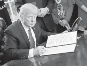  ?? PABLO MARTINEZ MONSIVAIS/ASSOCIATED PRESS ?? President Donald Trump signs an executive order requiring the Treasury Department to review the 2010 Dodd-Frank financial oversight law.