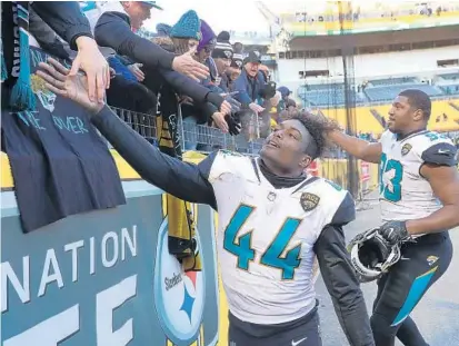  ?? ROB CARR/GETTY IMAGES ?? Jacksonvil­le linebacker Myles Jack (44) and defensive end Calais Campbell greet Jags fans after their thrilling 45-42 victory in Pittsburgh.