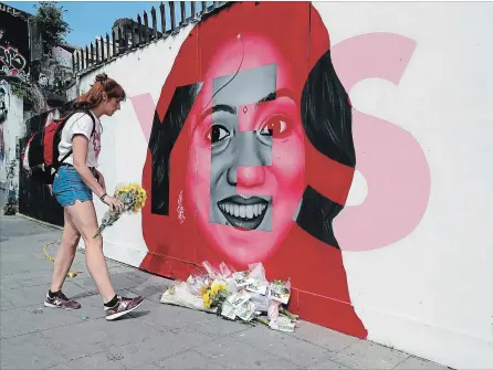  ?? NIALL CARSON THE ASSOCIATED PRESS ?? A woman places flowers by a mural showing Savita Halappanav­ar — a 31-year-old dentist who had sought and been denied an abortion and then died after a miscarriag­e — with the word YES over it, in Dublin, Ireland, on referendum day.