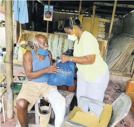  ??  ?? Icons official, Nurse Maxine Bendor Robinson hands out a care package to a resident of Annotto Bay.