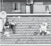  ?? PHOTO]
[AP FILE ?? Two workers take a nap on a roof in Madrid.