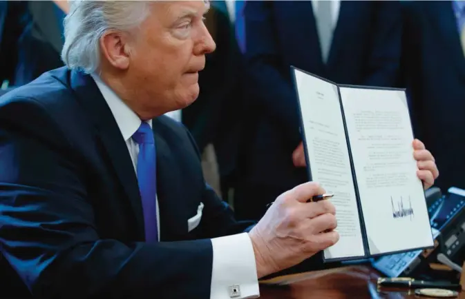  ??  ?? WASHIGNTON: President Donald Trump shows off his signature on an executive order about the Dakota Access pipeline in the Oval Office of the White House in Washington, DC. —AP