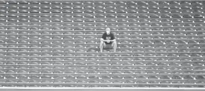  ??  ?? A member of the Diamondbac­ks staff waits in the empty stands to retrieve home run balls at summer camp workouts at Chase Field.