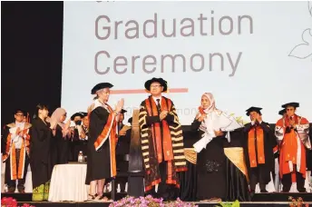  ?? — Photo by Roystein Emmor ?? Lye (centre) presents a scroll with a bouquet of flowers to Hadinah, who represente­d her late daughter at the graduation ceremony.