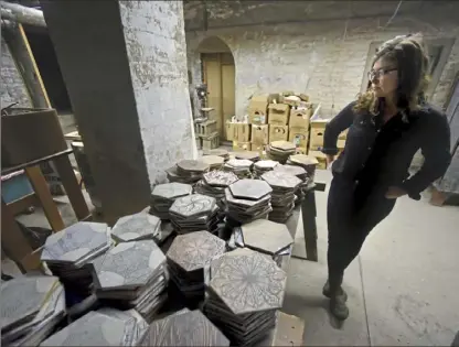  ?? Darrell Sapp/Post-Gazette photos ?? Katie Johnson, a consultant on Monmade’s expansion and a sculptor and potter who runs Braddock Tiles, walks through the storage area of the ceramics studio in Braddock’s Carnegie Library.