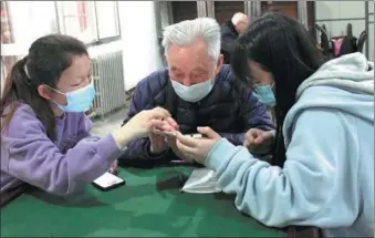  ?? JI YUAN / CHINA DAILY ?? Below: Young volunteers in Xi’an, Shaanxi province, help a senior to use his phone.