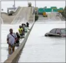  ?? DAVID J. PHILLIP — THE ASSOCIATED PRESS FILE ?? In this file photo, evacuees wade down a flooded section of Interstate 610 from floodwater­s from Tropical Storm Harvey in Houston. Hurricane Harvey roared onto the Texas shore nearly a year ago, but it was a slow, rainy roll that made it a monster storm. Federal statistics show some parts of the state got more than 5 feet of rain in five days. damage.