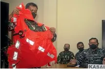  ??  ?? A military officer displays a life jacket found in the waters during a search for the Indonesian Navy submarine KRI Nanggala.