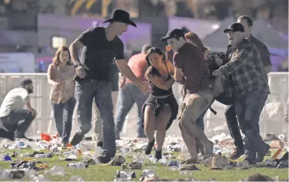  ?? DAVID BECKER, GETTY IMAGES ?? People carry a person at the Route 91 Harvest country music festival after gunfire erupted Sunday in Las Vegas. About 22,000 people were in the crowd when the shooting began from a hotel room at the Mandalay Bay Resort and Casino.