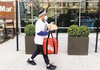  ?? Noah Berger / Special to The Chronicle ?? Grubhub driver David Augusta carries an order from alaMar in Oakland. Uber reportedly is seeking to buy Grubhub in an effort to strengthen its hold on the mealdelive­ry market.