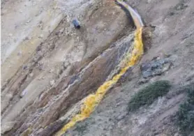  ??  ?? Wastewater flows from a trough and down a steep ravine at the site of the blowout at the Gold King mine in 2015.