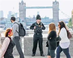  ??  ?? A watchful eye: commuters walking past a police officer on London Bridge on Monday