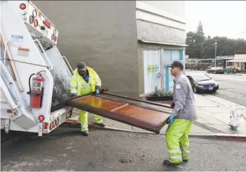  ?? Lea Suzuki / The Chronicle ?? Oakland workers Ayinde Osayaba (left) and David Conti load a discarded headboard into a truck.