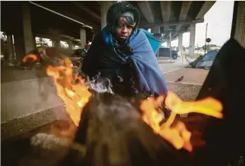  ?? Michael Ciaglo / Houston Chronicle ?? Tonya Sampson, who received a blanket from Star of Hope’s Love in Action van, tries to warm up by a fire under the Eastex Freeway as temperatur­es hover in the 30s on Tuesday.