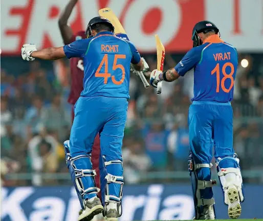  ?? AFP ?? Rohit Sharma (left) celebrates with Virat Kohli after completing his century during the first ODI against West Indies in Guwahati. —