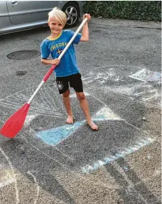  ??  ?? Lauri Joona, 8 Jahre, aus Neusäß übt schon einmal trocken das Stand up Paddlen auf seinem selbst gemalten Brett.