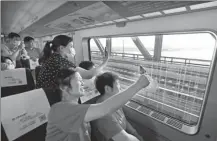  ?? YIN LIQIN / CHINA NEWS SERVICE ?? Passengers take photos of the Shanghai-Suzhou-Nantong Yangtze River Bridge on a train from Shanghai to Nantong as both the bridge and the Shanghai-Suzhou-Nantong Railway opened on Wednesday.