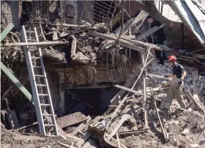  ?? AP ?? Emergency personnel inspect a destroyed house Saturday after a Russian attack in a residentia­l neighborho­od in Kharkiv, Ukraine.