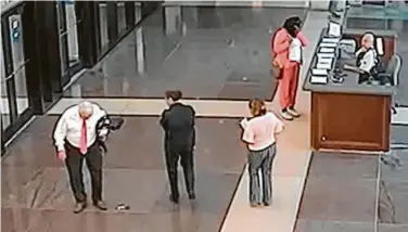  ?? Cook County Sheriff’s Office / Associated Press ?? In a photo taken from a surveillan­ce video, Cook County Circuit Judge Joseph Claps, left, looks down at the pistol he allegedly dropped in the lobby of the courts building July 3 in Chicago.