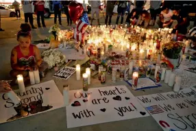  ??  ?? A girl places candles at a memorial for victims of the mass shooting in Las Vegas on Tuesday. A gunman opened fire on an outdoor music concert on Sunday in the deadliest mass shooting in modern US history.