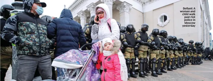  ??  ?? Defiant: A woman and child walk past riot police in Moscow yesterday