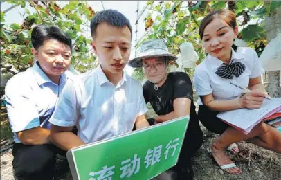  ?? ZHUO ZHONGWEI / CHINA NEWS SERVICE ?? Employees from Bank of Shangrao (second from left, right) help small-sized enterprise owners apply for loans in Shangrao, Jiangxi province, in September.