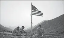  ?? DAVID GOLDMAN/AP ?? U.S. soldiers sit beneath an American flag on Sept. 11, 2011, at Forward Operating Base Bostick in Kunar province, Afghanista­n. A soldier deployed there asks for support for the newspaper Stars and Stripes.