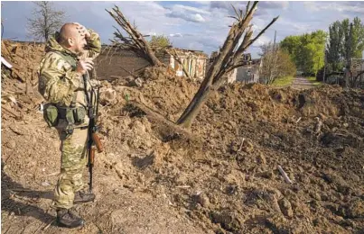  ?? EVGENIY MALOLETKA AP ?? A Ukrainian serviceman inspects a site after an airstrike by Russian forces in Bakhmut, Ukraine, on Tuesday. The city is in the Donetsk region, part of Ukraine’s eastern industrial heartland that the Russian military is targeting.