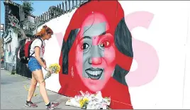  ?? AP ?? A woman places flowers at a mural showing late Indian dentist Savita Halappanav­ar.