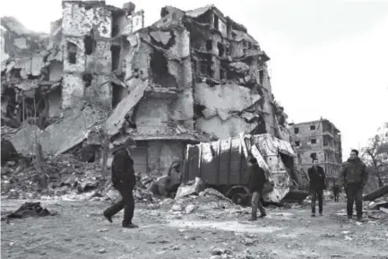  ??  ?? Syrians walk along a destroyed street in the old city of Aleppo on Saturday as pro-government forces reopen roads that were barricaded to divide rebel and government-held areas. Youssef Karwashan, AFP/Getty Images