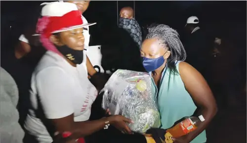  ??  ?? River Valley Properties owner Smelly Dube (left) hands over a food hamper to one of the beneficiar­ies