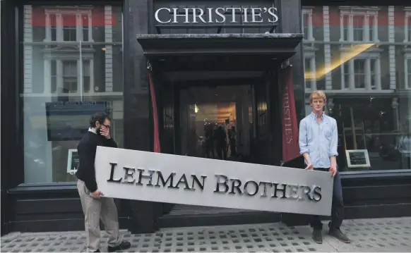  ??  ?? Employees of auction house Christie’s pose with a Lehman Brothers sign in central London on September 24, 2010